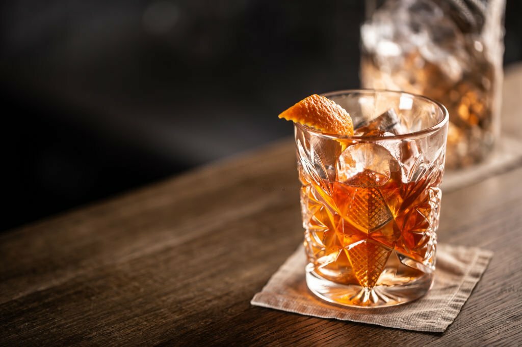 Old fashioned whiskey drink on ice with orange zest garnish. Cocktail culture