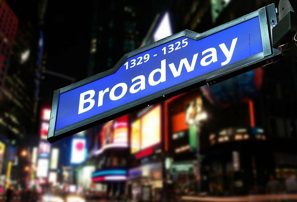 Broadway Sign and Blurred Lights of Broadway Avenue Behind.